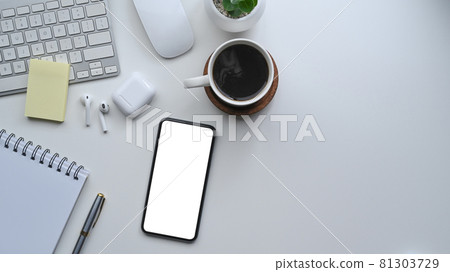 Above view smart phone with empty screen, wireless earphone and coffee cup on white desk. 81303729