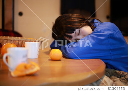 A woman sleeping on a kotatsu 81304353
