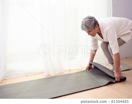 Mature Asian woman doing health care exercises on yoga mat at home Mature Asian woman doing health care exercises on yoga mat at home 81304885