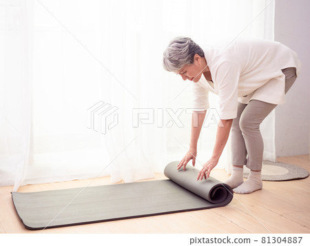 Mature Asian woman doing health care exercises on yoga mat at home Mature Asian woman doing health care exercises on yoga mat at home 81304887