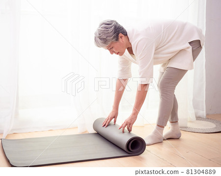 Mature Asian woman doing health care exercises on yoga mat at home Mature Asian woman doing health care exercises on yoga mat at home 81304889