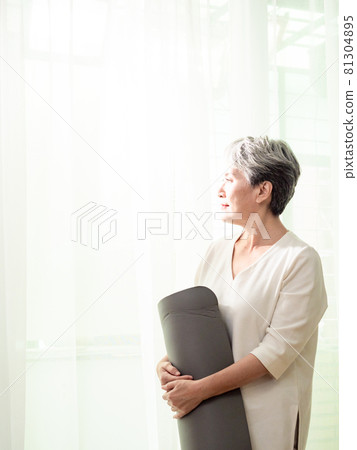 Mature Asian woman holding yoga mat exercising at home for health care Mature Asian woman holding yoga mat exercising at home for health care 81304895