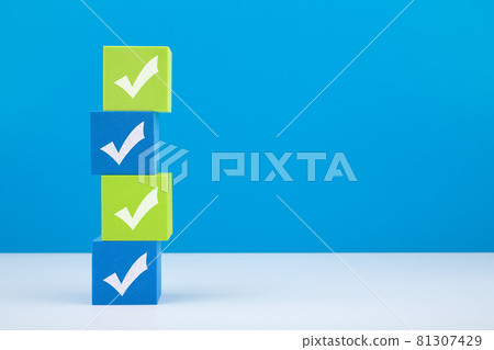Checkmarks on four light green and blue blocks on white table against blue background with copy space Checkmarks on four light green and blue blocks on white table against blue background with copy space 81307429