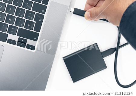 Hand connecting a External hard disk to a modern laptop computer. Top view 81312124