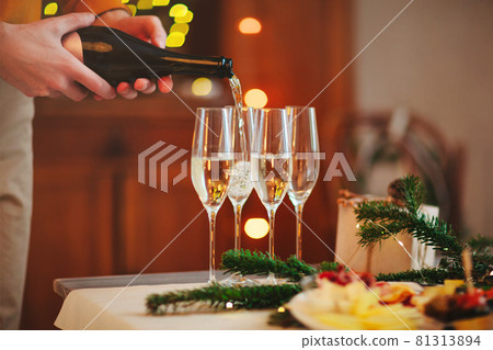 Glasses of champagne on wooden table with candles against blurred wall with Christmas decoration 81313894