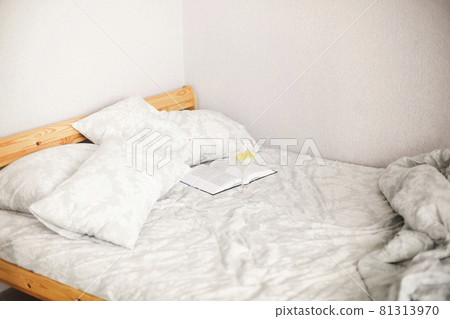 Side view of morning bed after awakening with open book and glass of lemon water 81313970