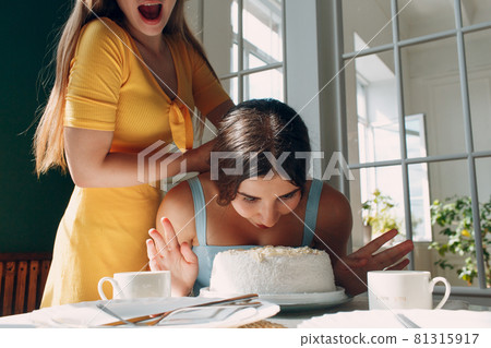 Young woman dips face in white cake with cream. Happy birthday concept. Young woman dips face in white cake with cream. Happy birthday concept. 81315917