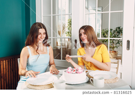 Women happy friends at home sitting and smiling with white birthday cake Women happy friends at home sitting and smiling with white birthday cake 81316025