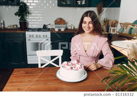 Young woman with dessert white cake sit at kitchen 81316332