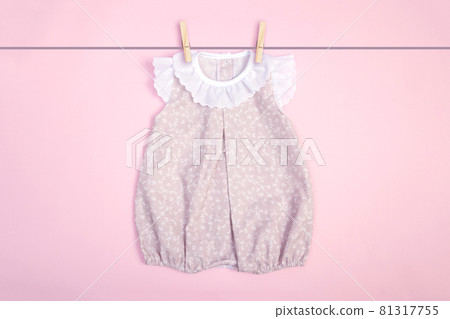 pink baby clothes hanging on pink background 81317755