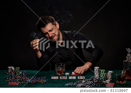 Bearded casino player man playing poker on green table 81318697
