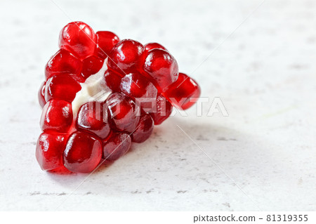 Closeup detail, cluster of red pomegranate fruits that looks like gems on white working board, space for text right. Closeup detail, cluster of red pomegranate fruits that looks like gems on white working board, space for text right. 81319355