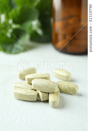 Herbal pills on white textured table, close up 81319790