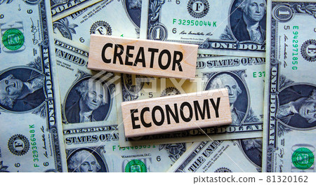 Creator economy symbol. Wooden blocks with words Creator economy on beautiful background from dollar bills, copy space. Business and creator economy concept. 81320162