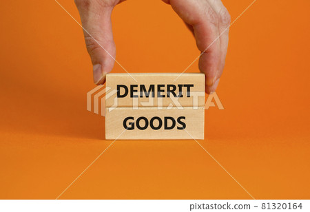 Demerit goods symbol. Wooden blocks with words Demerit goods on beautiful orange background, copy space. Businessman hand. Business and demerit goods concept. 81320164