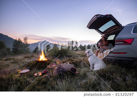 Woman traveling by car and having a picnic in the mountains Woman traveling by car and having a picnic in the mountains 81320297