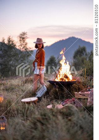 Woman at picnic with bonfire in the mountains Woman at picnic with bonfire in the mountains 81320310