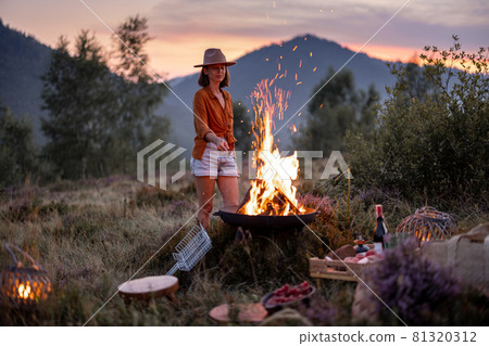 Woman at picnic with bonfire in the mountains 81320312