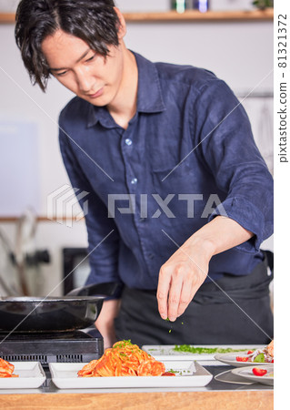 Young man cooking boy image in an apron with parsley on tomato pasta Young man cooking boy image in an apron with parsley on tomato pasta 81321372