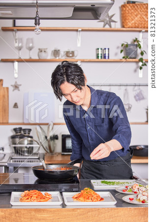 Young man cooking boy image in an apron with parsley on tomato pasta Young man cooking boy image in an apron with parsley on tomato pasta 81321373