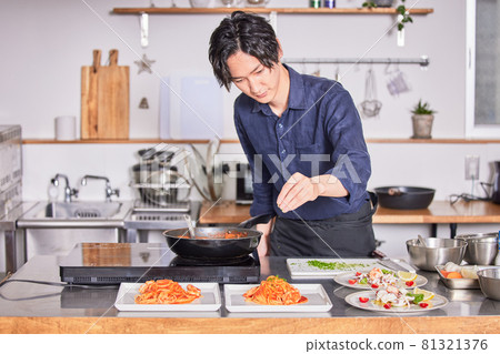 Young man cooking boy image in an apron with parsley on tomato pasta Young man cooking boy image in an apron with parsley on tomato pasta 81321376