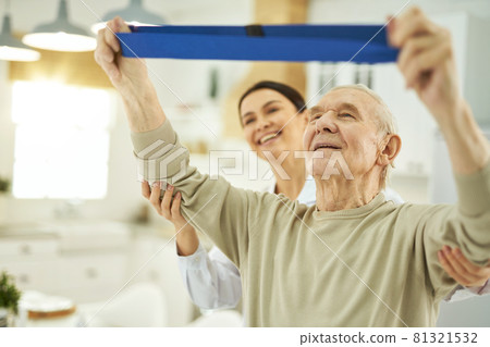 Happy young nurse helping an elderly man to do exercises in room Happy young nurse helping an elderly man to do exercises in room 81321532