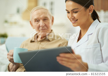 Nurse and senior citizen looking at tablet screen at home Nurse and senior citizen looking at tablet screen at home 81321535