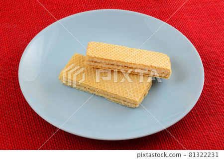 Two taro cream wafer cookies on blue snack plate on red background 81322231