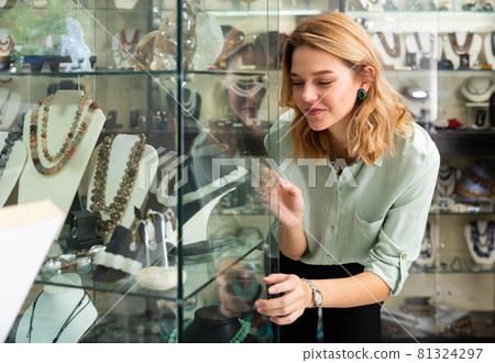 Female client admiring jewelry in glass showcase Female client admiring jewelry in glass showcase 81324297