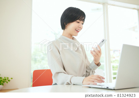 在辦公室使用智能手機的女商人 在辦公室使用智能手機的女商人 81324923