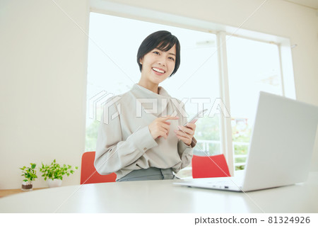 在辦公室使用智能手機的女商人 在辦公室使用智能手機的女商人 81324926