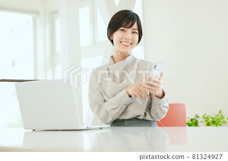 在辦公室使用智能手機的女商人 在辦公室使用智能手機的女商人 81324927