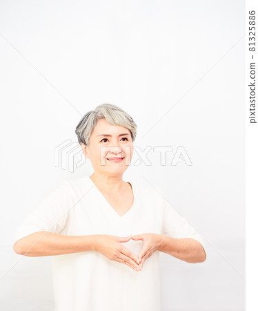 一個成熟美麗的白髮女子,頭髮花白,袖子閉合,臉上掛著一個手形的心形標誌,臉上帶著微笑。 浪漫的概念。 一個成熟美麗的白髮女子,頭髮花白,袖子閉合,臉上掛著一個手形的心形標誌,臉上帶著微笑。 浪漫的概念。 81325886