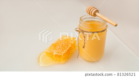 Honey dipper and jar of creamed amber organic honey bee harvest next to fresh honeycomb healthy food banner panorama 81326521