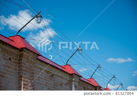 Barbed wire on the fence of the prison against the blue sky 81327804