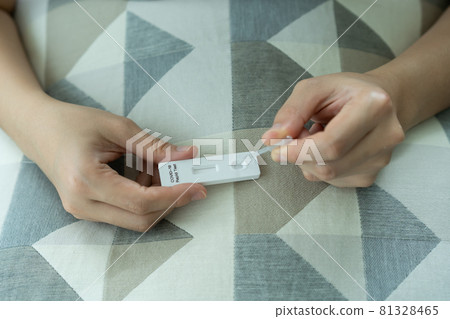 Asian young woman teasing a COVID-19 antigen test at home. Asian young woman teasing a COVID-19 antigen test at home. 81328465