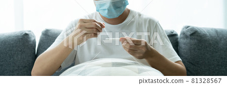 Asian young man testing a COVID-19 antigen test at home. Asian young man testing a COVID-19 antigen test at home. 81328567