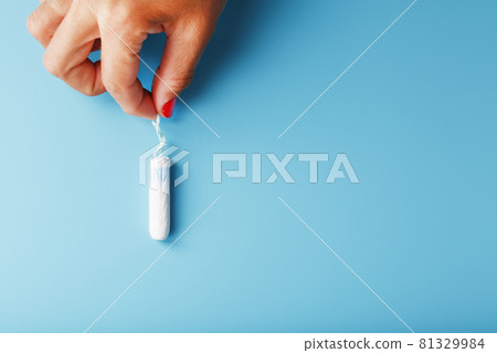 A female sanitary swab in her hand on a blue background with a free space A female sanitary swab in her hand on a blue background with a free space 81329984