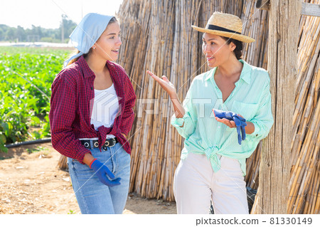 Asian woman farmer talking friendly to her young female companion in farm 81330149