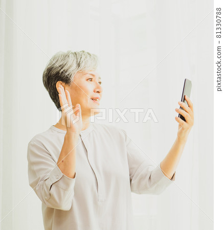 一位成熟的白髮亞裔女性利用這個機會進行愉快的交談或觀看會議。 81330788