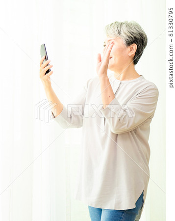 A mature gray-haired woman of Asian descent uses the opportunity to have a pleasant conversation or viewing meeting. 81330795