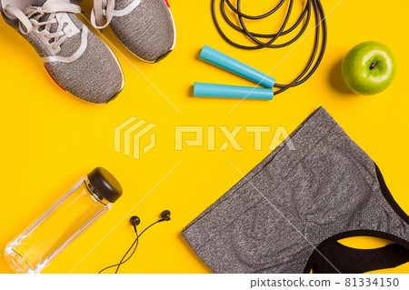 Fitness accessories on yellow background. Sneakers, bottle of water, headphones and sport top. Fitness accessories on yellow background. Sneakers, bottle of water, headphones and sport top. 81334150