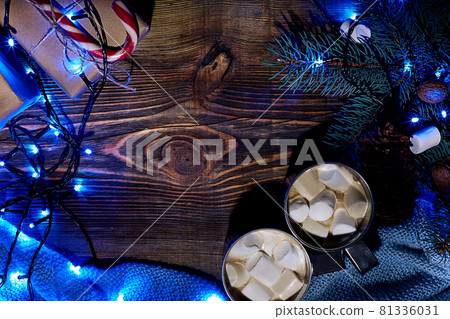 Christmas hot drink. Cocoa with marshmallow, garland and spruce branches on a wooden background. Top view 81336031