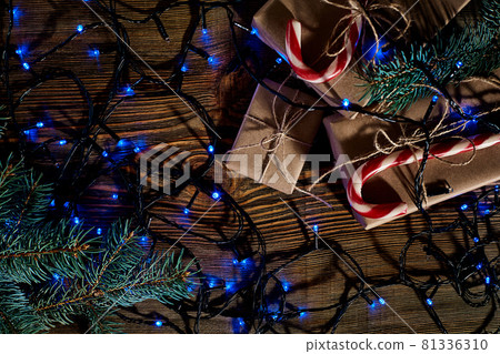 Christmas wooden background with fir tree. Christmas tree branch with decorations on wood background and garland. 81336310