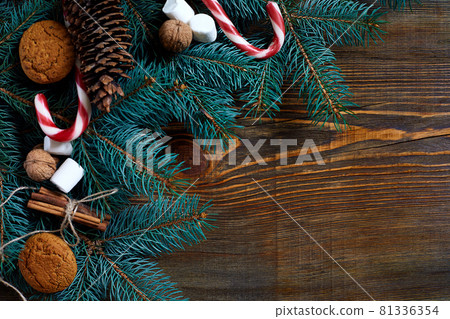 Christmas or New Year background with cookies, spices, cinnamon, nuts and fir tree branch on dark wooden background. Christmas or New Year background with cookies, spices, cinnamon, nuts and fir tree branch on dark wooden background. 81336354
