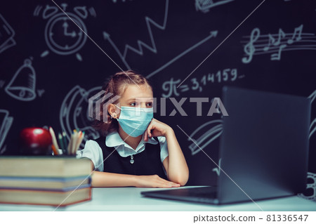 Junior student wearing medical mask online virtual learning language class on laptop. 81336547