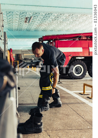 Firefighter wearing uniform in fire station Firefighter wearing uniform in fire station 81336943