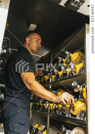 Male firefighter holding fire extinguisher in truck Male firefighter holding fire extinguisher in truck 81336947
