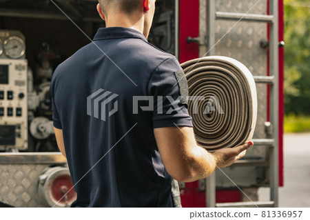 Fitefighter standing by truck holding special equipment 81336957