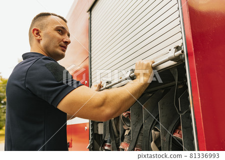 Fireman standing by firefighting truck with special tools Fireman standing by firefighting truck with special tools 81336993
